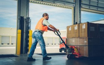 worker pushing an hydraulic hand pallet truck on a warehouse